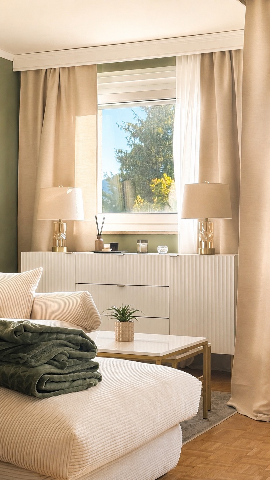 Wohnzimmer mit Cord-Sofa, Leinenvorhängen, Sideboard und goldenen Tischleuchten